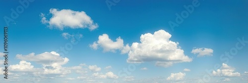 Vibrant blue sky with a few puffy white clouds and some flat grey clouds on the horizon, blue skies, layered clouds