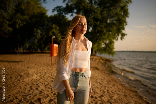 slender middle-aged blonde walks along the summer beach and looks into the distance photo