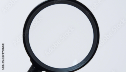 The image displays a magnifying glass with a round, clear lens and a black handle. It is positioned against a neutral background. There are no texts or additional objects visible in the image.