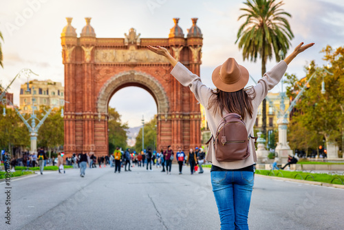 A happy tourist woman looks at the famous Arc de Triomf in Barcelona, Spain, on her sightseeing trip through the city photo