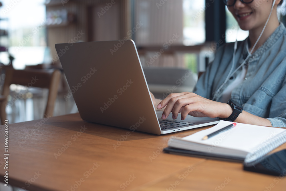 Happy business woman wearing earphone, working on laptop computer, video confrenec via online meeting app at coffee shop. Student studying online class via laptop Happy business woman wearing earphone, working on laptop computer, video confrenec via online meeting app at coffee shop. Student studying online class via laptop