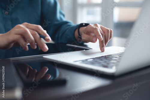 Close up, business woman working on laptop computer, internet networking and searching the information at office with digital tablet and mobile phone on office table.