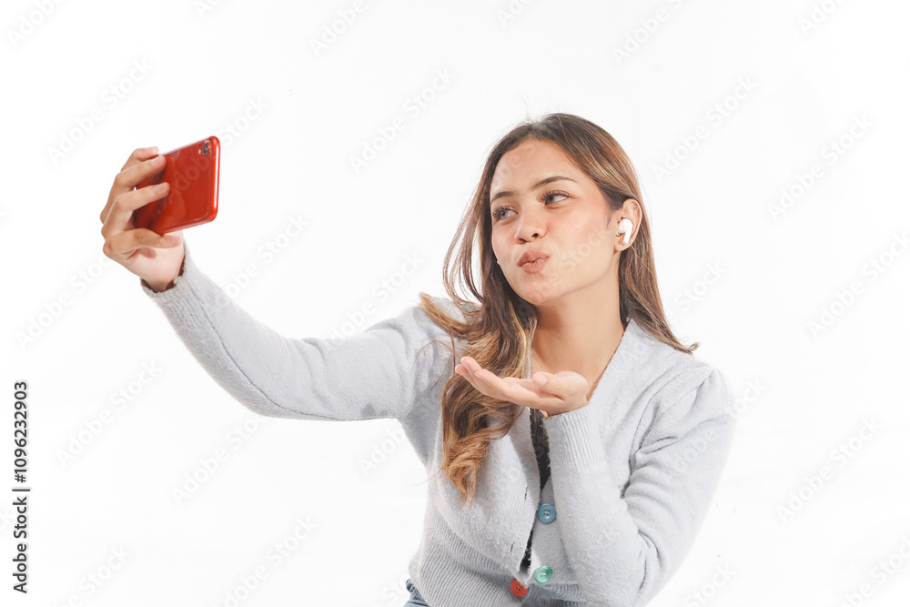close up Young Asian woman sitting cross-legged taking a blowing kisses selfie while using airpods close up Young Asian woman sitting cross-legged taking a blowing kisses selfie while using airpods