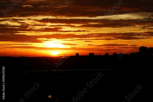 Sunrise or sunset with orange sky background over city silhouette.