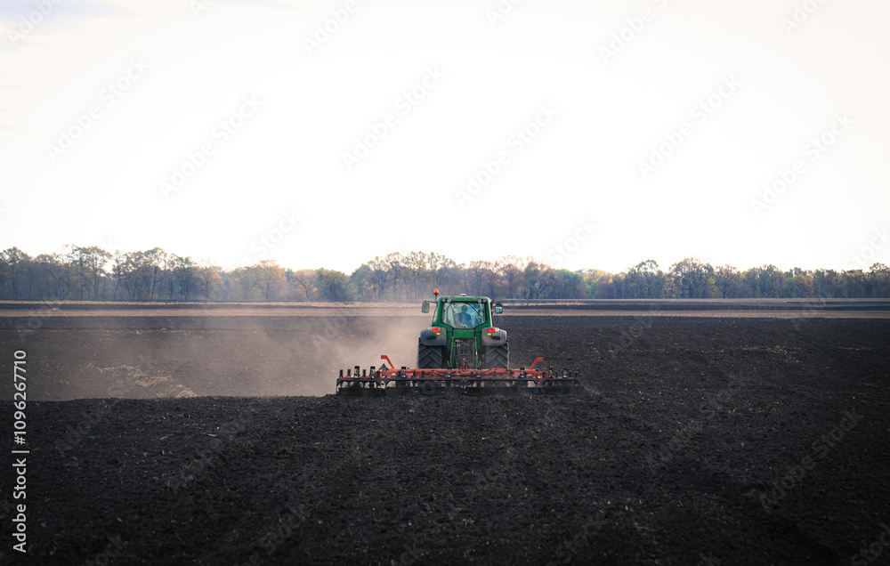 A powerful tractor plows a fertile field, raising clouds of dust against a clear blue sky, symbolizing hard work in agriculture and the beauty of rural life and industriousness of farmers A powerful tractor plows a fertile field, raising clouds of dust against a clear blue sky, symbolizing hard work in agriculture and the beauty of rural life and industriousness of farmers