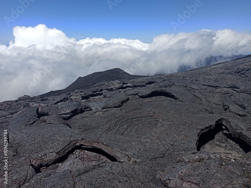 lava earth crust and scorched volcanic landscape on Piton de la Fournaise, La Réunion island. Basaltic rocks above the clouds  photo
