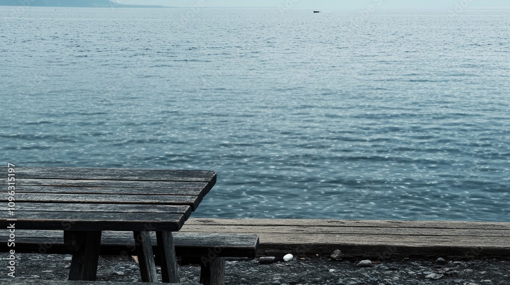 Vacant wooden table by serene shoreline with calm water and clear sky, ideal for text overlay and peaceful reflection. Vacant wooden table by serene shoreline with calm water and clear sky, ideal for text overlay and peaceful reflection.