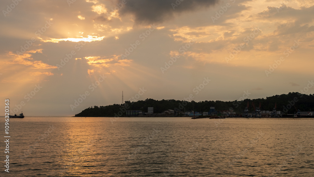 harbor scene with industrial factories and construction cranes and cargo ships sailing in the orange afternoon sunlight harbor scene with industrial factories and construction cranes and cargo ships sailing in the orange afternoon sunlight