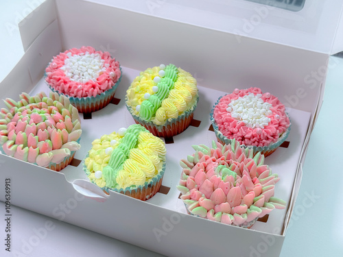 A close-up of six cupcakes with unique floral frosting designs. Each cupcake is carefully crafted with pastel colors and topped with piped flower shapes, pearls, and delicate sprinkles, perfect for an