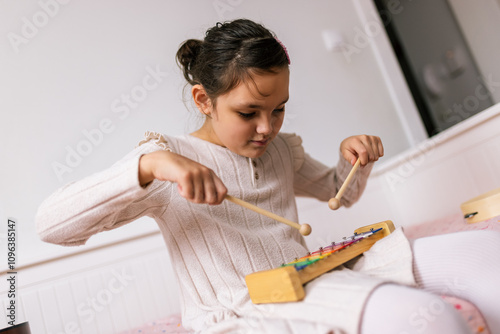 Little girl with autism plays metallophone. Music therapy at home. photo