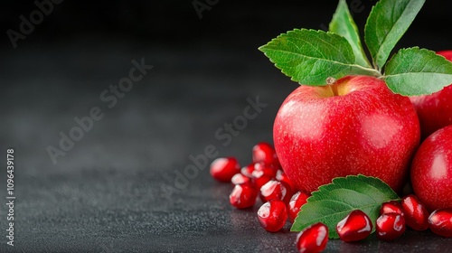  three red apples with green leaves and pomegranate seeds on a black background The apples are vibrant and the leaves are a deep green, while the pomegrate seeds ar photo