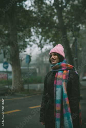 A Woman in a Cozy Winter Outfit Stands Against a Captivating Foggy Urban Background
