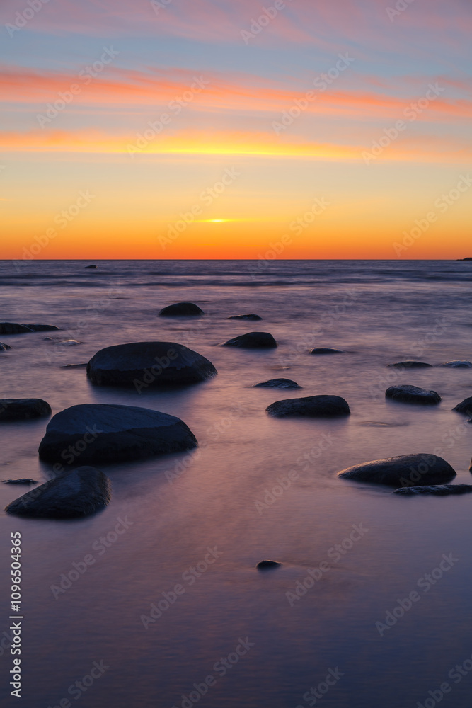 Sunset on the coast of the Baltic Sea. Stones on the shallow sea shore. Sunset on the coast of the Baltic Sea. Stones on the shallow sea shore.