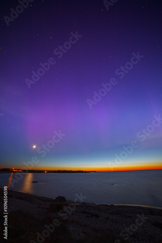 Display of purple and pink aurora borealis over the Baltic sea in Estonia. Sunset stripe on the horizon photo