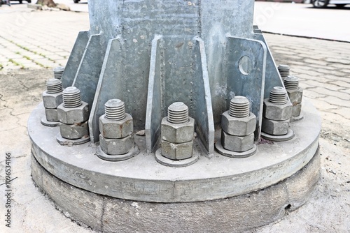 Metal pillar bolted to concrete foundation of street public spotlight pole