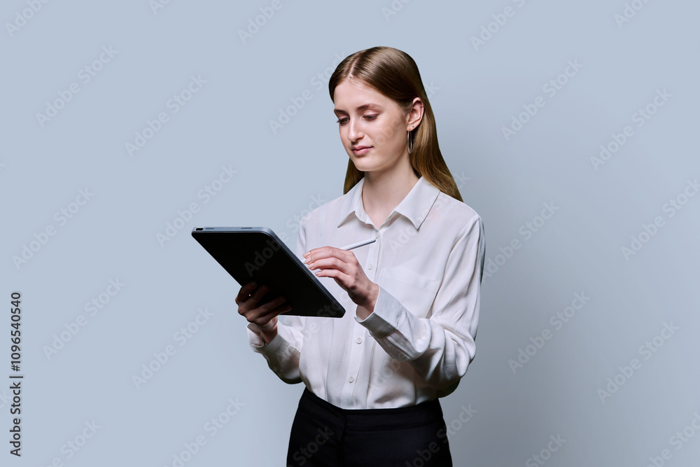Teenage female student using digital tablet on gray studio background Teenage female student using digital tablet on gray studio background