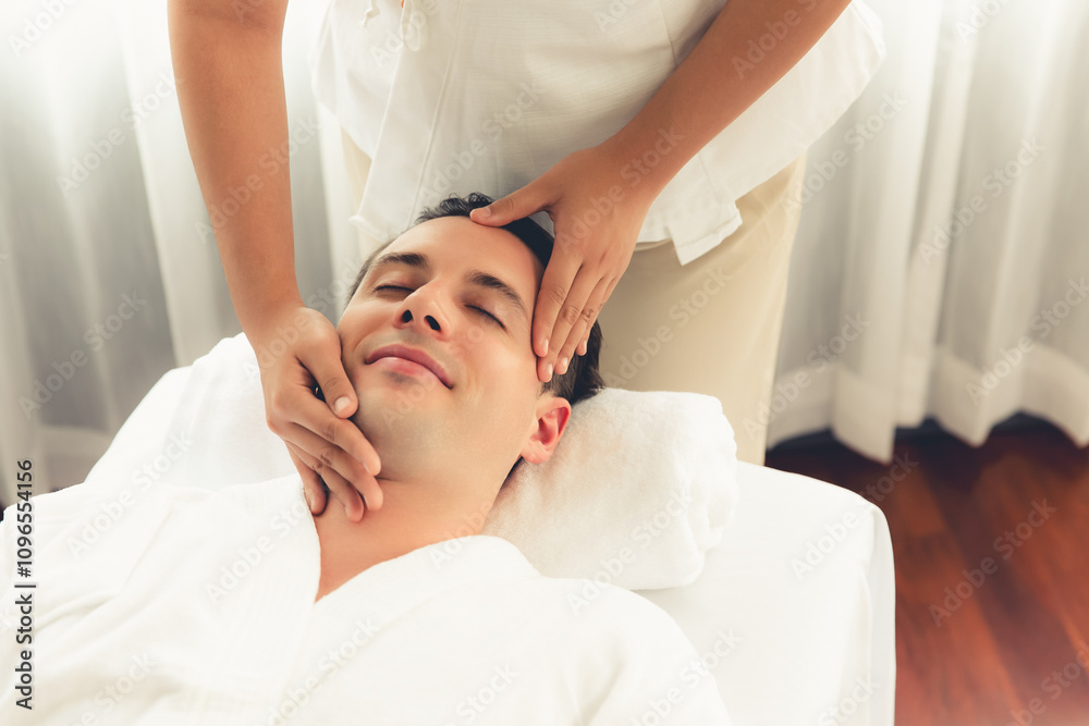 Caucasian man enjoying relaxing anti-stress head massage and pampering facial beauty skin recreation leisure in dayspa modern light ambient at luxury resort or hotel spa salon. Quiescent Caucasian man enjoying relaxing anti-stress head massage and pampering facial beauty skin recreation leisure in dayspa modern light ambient at luxury resort or hotel spa salon. Quiescent