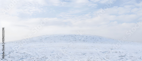 "Serene Snow-Covered Hill Beneath a Soft Pale Sky: A Tranquil Winter Landscape Scene Unveiled"