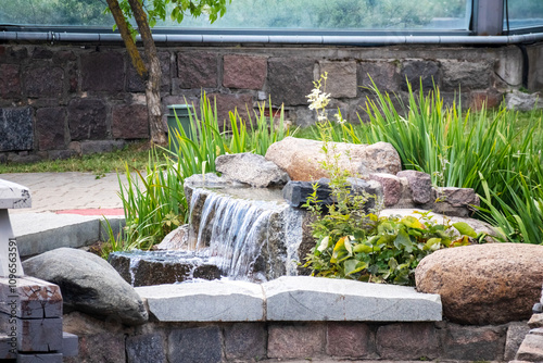 
A fountain in the middle of a stone garden with flowers