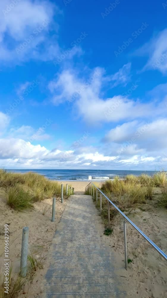 footpath over sand dunes and beach grass to the blue sea, sunny day in spring season footpath over sand dunes and beach grass to the blue sea, sunny day in spring season