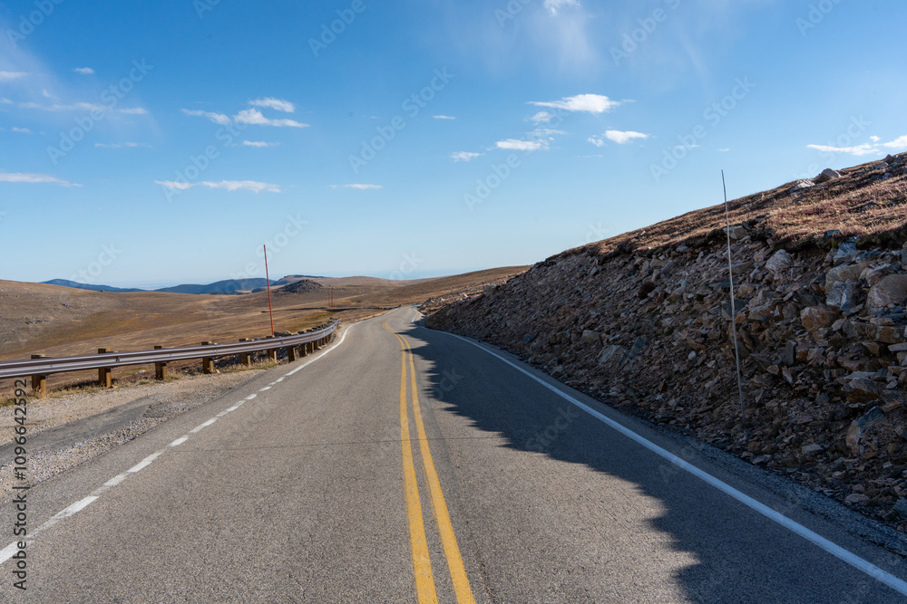 Beartooth Highway in Summer shows road hugging the side of a huge mountain on a hazy summer day Beartooth Highway in Summer shows road hugging the side of a huge mountain on a hazy summer day