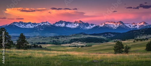 Scenic sunset landscape with vibrant colors illuminating mountain peaks and lush green meadows in a tranquil outdoor setting.