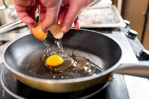 Wallpaper Mural A pair of hands cracking an egg over a frying pan, with the yolk and some egg white already in the pan. Ideal for culinary content, cooking tutorials, or breakfast recipes. Clean, close-up shot Torontodigital.ca