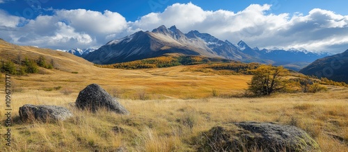 Scenic mountain landscape with golden grass fields and dramatic clouds under a clear blue sky in autumn season photo