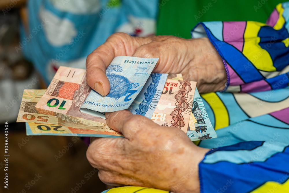 Brazil money. Senior woman holding Brazilian reals in hands. Financial and economic concept. Financial situation of retirees in Brazil