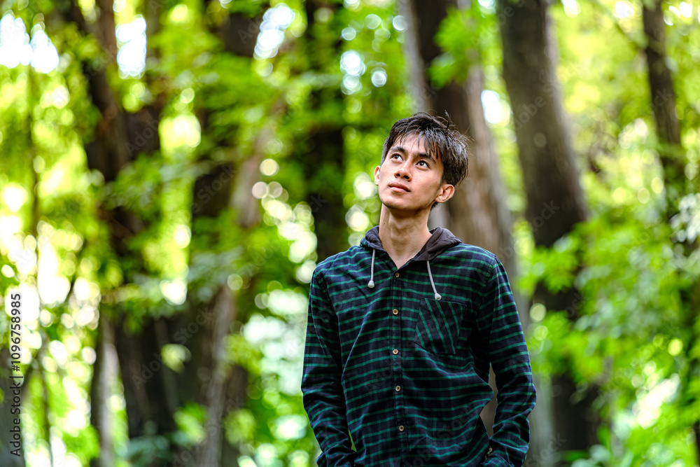 Handsome man standing alone while looking around. Beautiful dramatic deep forest greenery Handsome man standing alone while looking around. Beautiful dramatic deep forest greenery