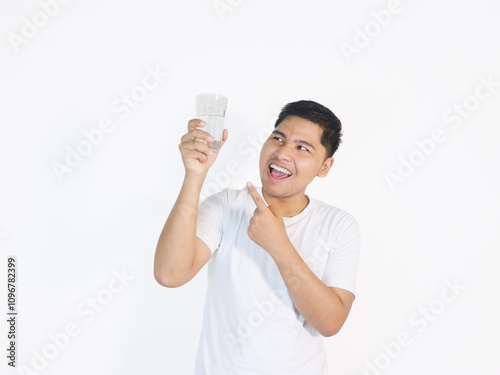 Adult Asian man looking to the glass of water that he hold photo