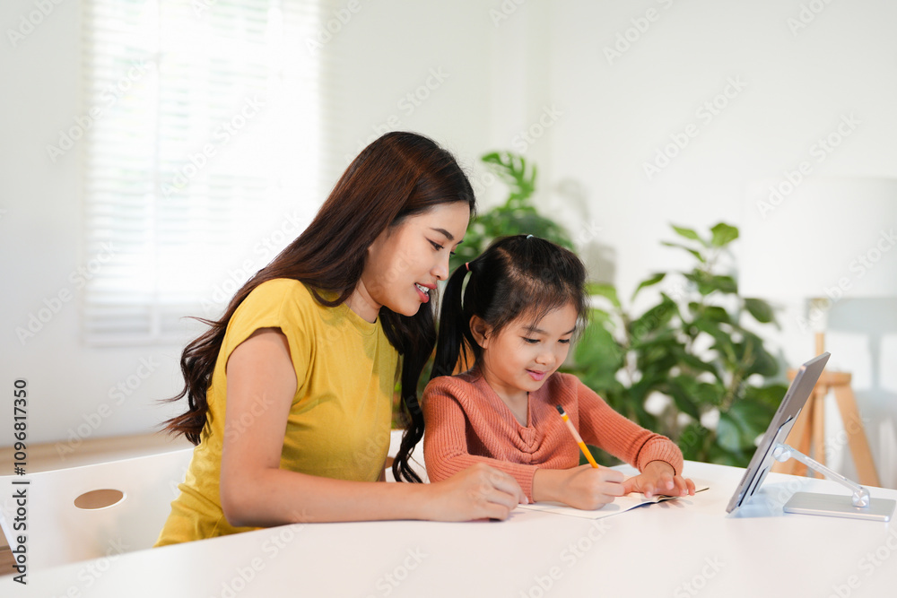 Loving young mum and little preschooler daughter sit at table using laptop tablet together, caring mother help small girl child teaching learning online on computer, kids and technology concept Loving young mum and little preschooler daughter sit at table using laptop tablet together, caring mother help small girl child teaching learning online on computer, kids and technology concept