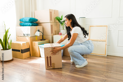 Profile view of a woman squating and showing the proper way to lift a heavy box while moving into ner new apartmetn photo