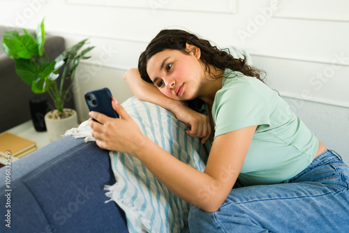 Teen girl feeling anxious while using her phone and waiting for a text message or reply photo