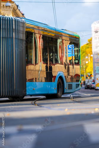 Blue articulated bus driving through a crossing in the city. photo