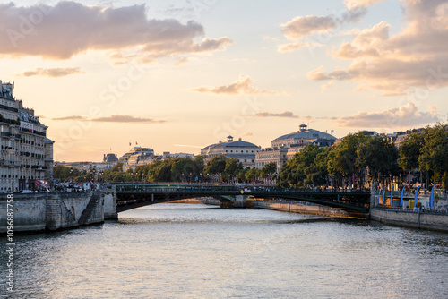 A beautiful view of Paris at sunset, with the river gently flowing beneath a historic bridge. The warm golden hues of the setting sun reflect off the water, creating a serene and romantic atmosphere. photo