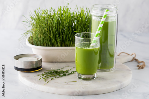 A glass of freshly poured wheatgrass juice with a glass pitcher of it in behind. photo