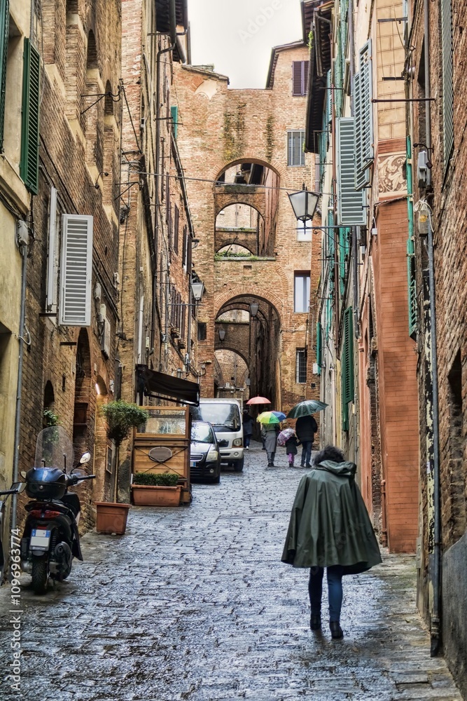 siena, italien - pittoreske gasse mit torbogen an einem regentag