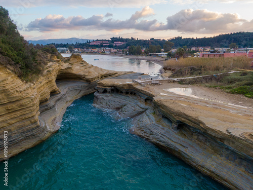 Sandstone cliffs, covered by fresh greenery, creating a bay Canal d Amour (Love Channel). Waves of the Ionic sea. Blue sky with white clouds. Sidari, Corfu, Greece. photo