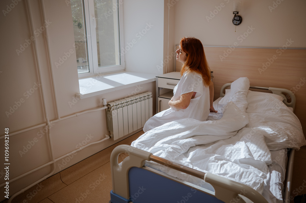 An unhappy pregnant woman sits on a couch in a hospital room. An unhappy pregnant woman sits on a couch in a hospital room.