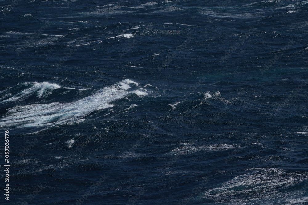 Fototapeta premium Dark ocean waves with white foam creating dynamic seascape. turbulent water reflects power and beauty of nature