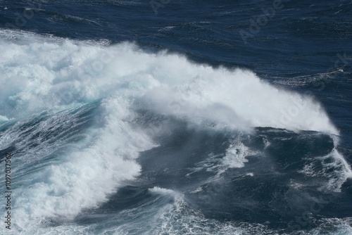 Powerful ocean waves crashing against each other, creating dramatic seascape. deep blue water contrasts with white foam, showcasing nature raw energy