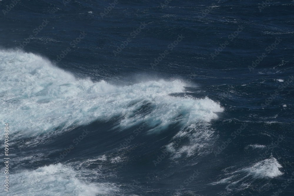 Waves crashing on dark ocean surface, creating dynamic and powerful scene. contrast of white foam against deep blue water evokes sense of nature strength and beauty Waves crashing on dark ocean surface, creating dynamic and powerful scene. contrast of white foam against deep blue water evokes sense of nature strength and beauty
