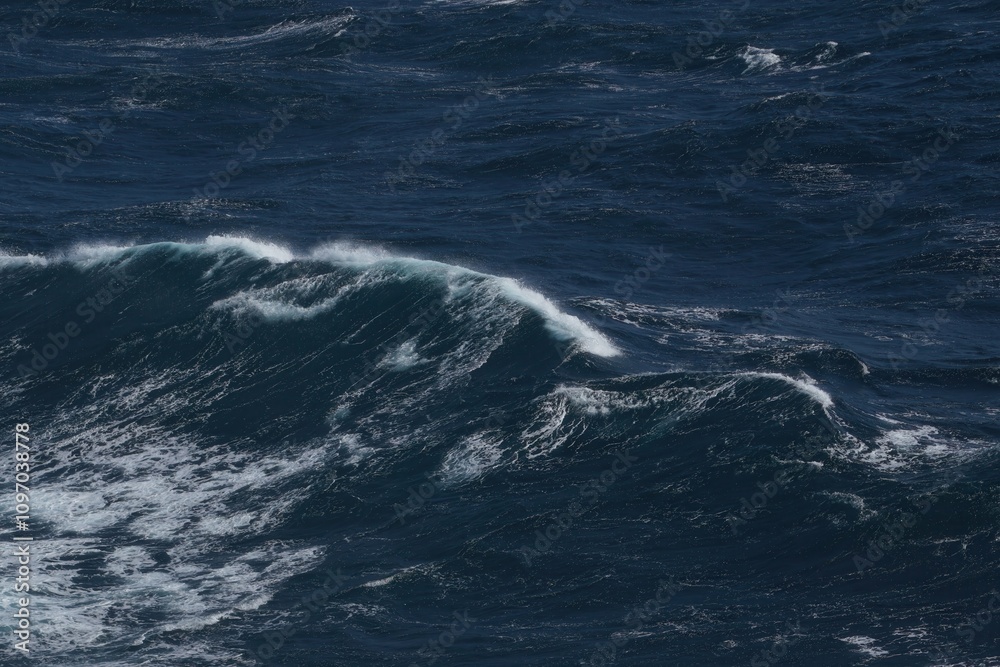 Naklejka premium Dark ocean waves crashing against each other, creating dynamic seascape. deep blue water reflects light, showcasing power of nature