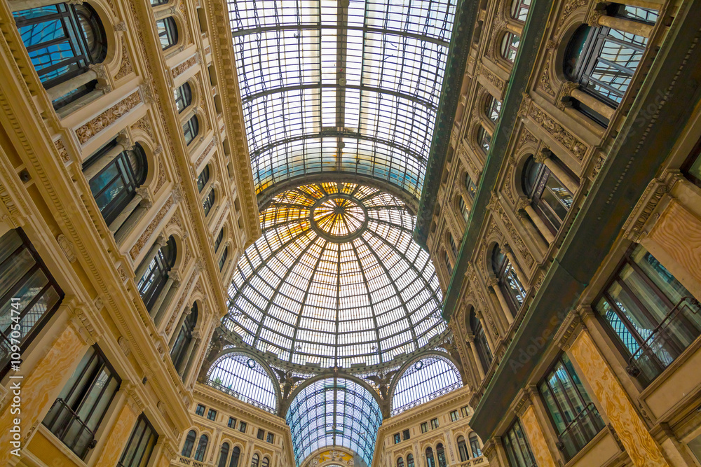 The photo features the stunning Umberto I Gallery in Naples, highlighting its elegant glass dome, intricate architecture, and bustling atmosphere.
