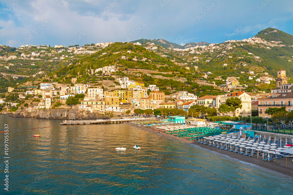 Fototapeta premium This image showcases Minori on the Amalfi Coast, with its charming seaside houses, tranquil beach, and lush green hills, bathed in the warm Mediterranean light.