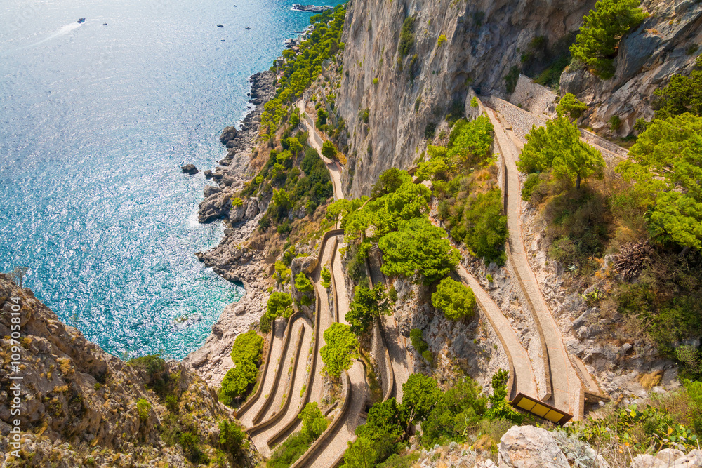 Captured on Capri Island, the photo reveals the historic Phoenician Steps, a steep stone staircase surrounded by natural beauty, leading up the cliffs with panoramic sea views.