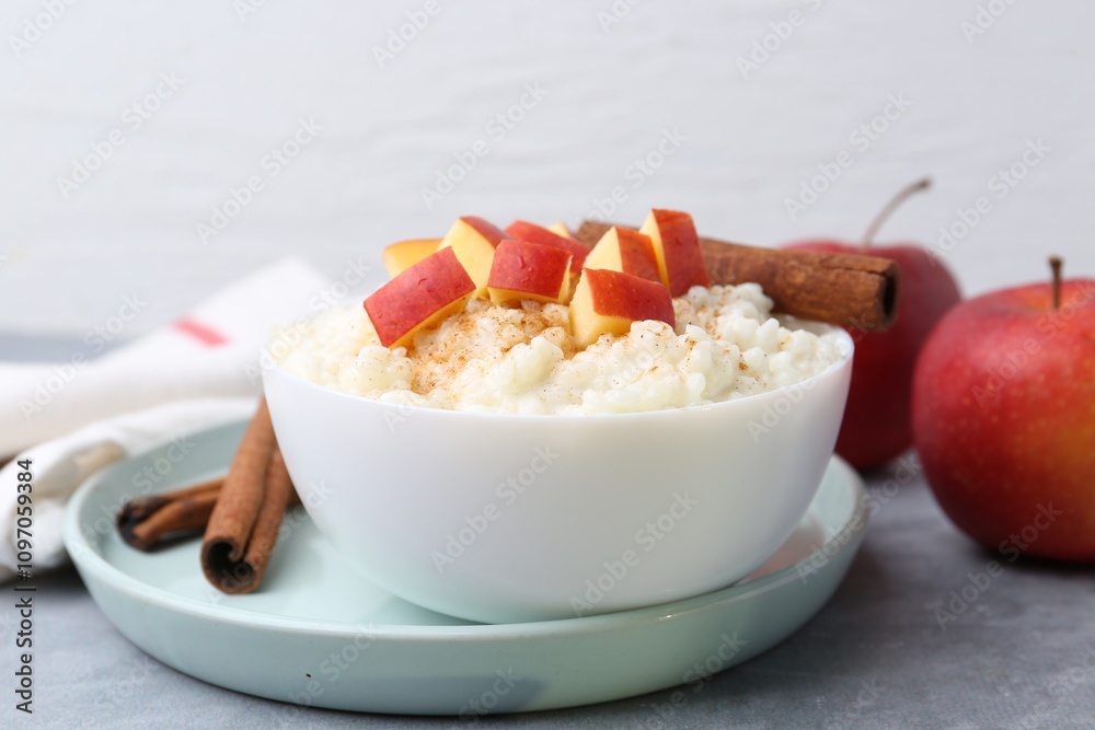 Delicious rice pudding with apples and cinnamon on grey table Delicious rice pudding with apples and cinnamon on grey table
