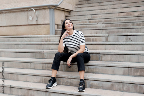 Happy and cheerful woman sitting on concrete stairs outdoors