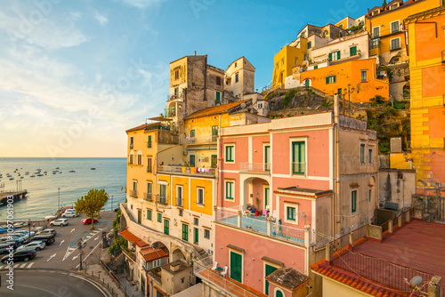 Obraz na płótnie The photo captures a sunny view of Minori on the Amalfi Coast, showcasing its charming coastal buildings, sandy beach, and surrounding green hills under a clear blue sky. w salonie